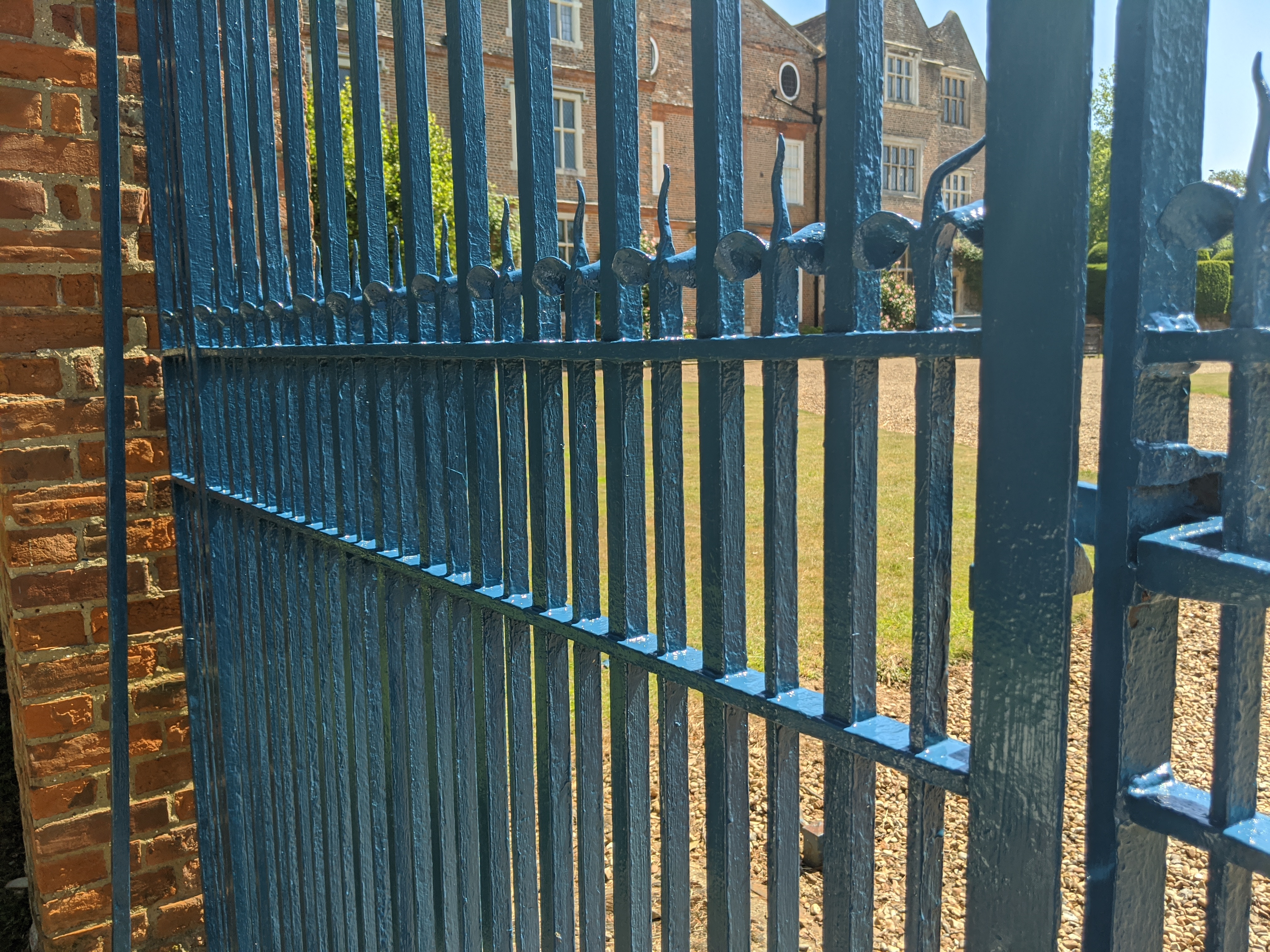 Freshly painted estate gates in dark blue with manor house behind
