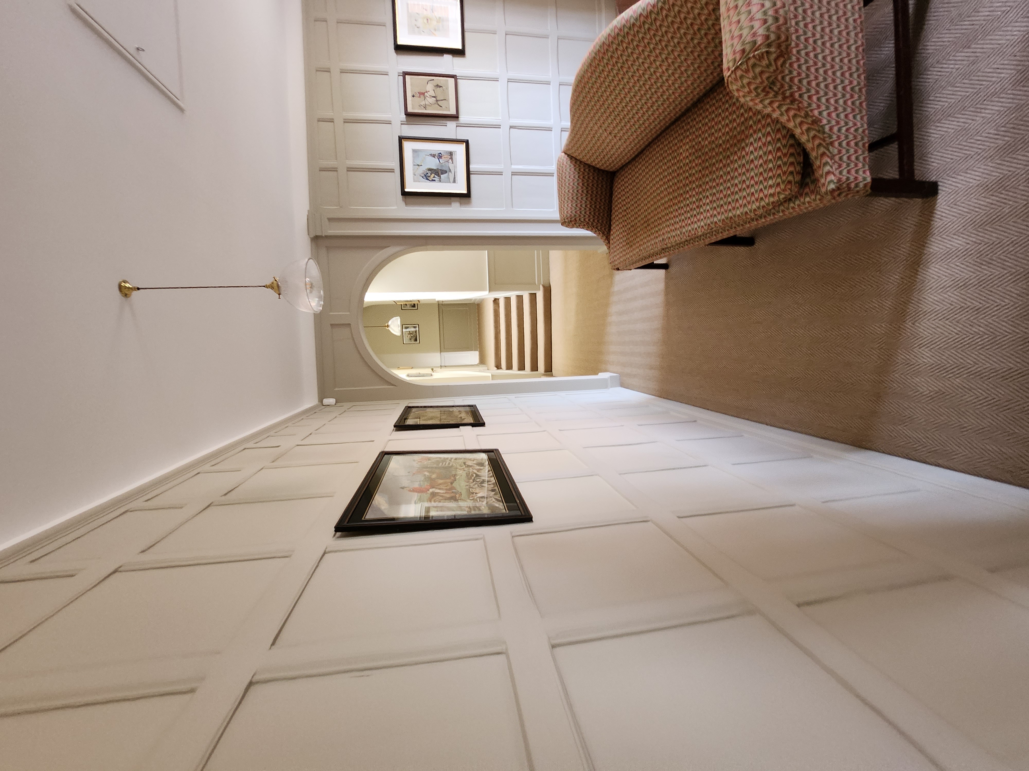 Hallway with painted panelled flooring, arched opening and framed prints