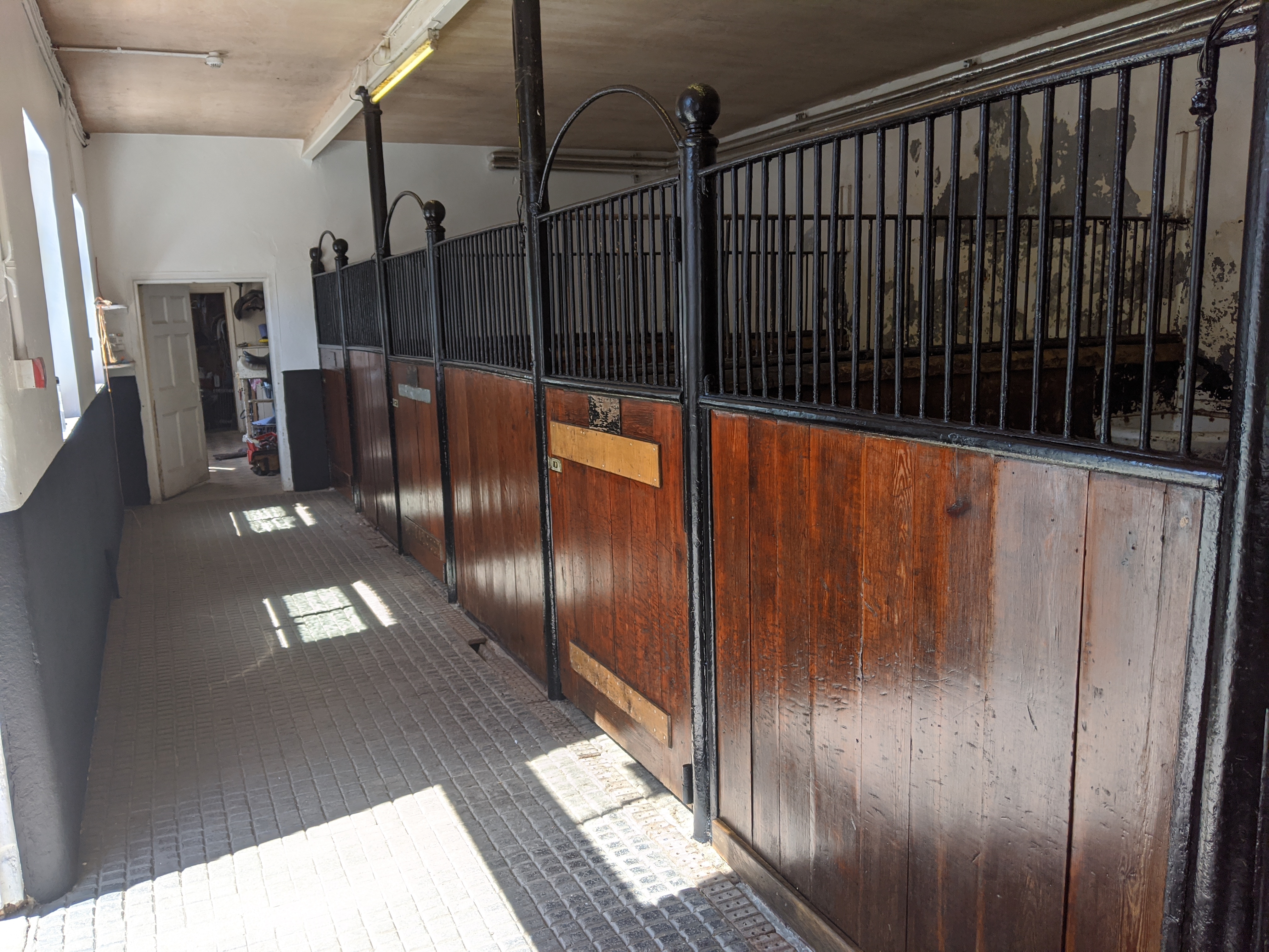 Restored horse stalls — varnished timber panels and repainted iron railings