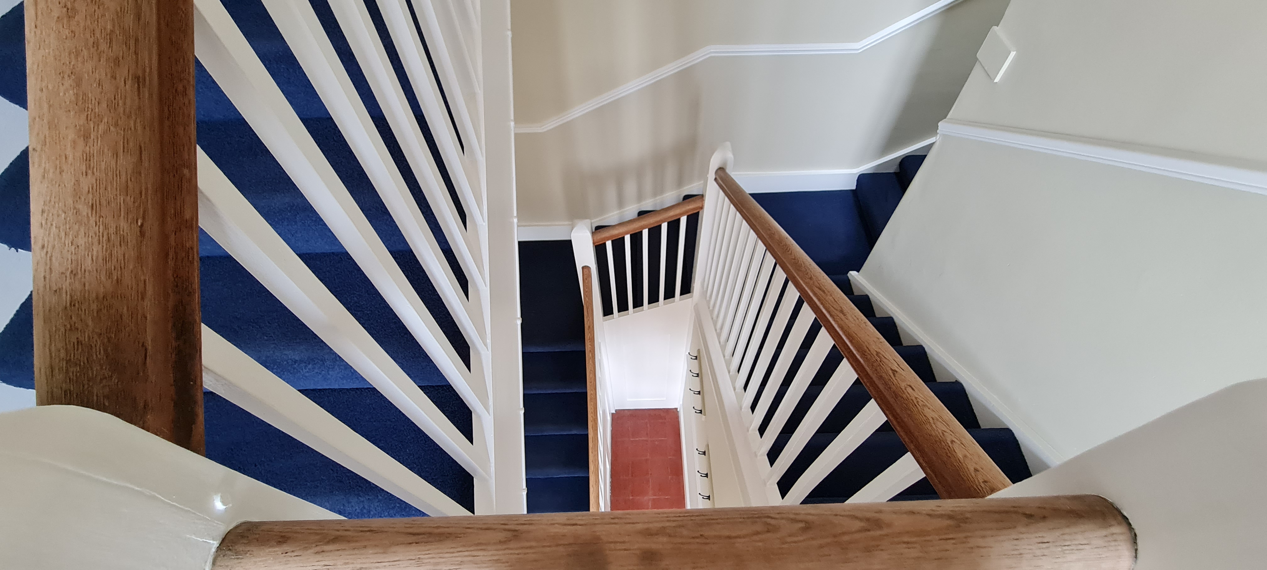 Overhead view of staircase with navy carpet and white painted balustrade
